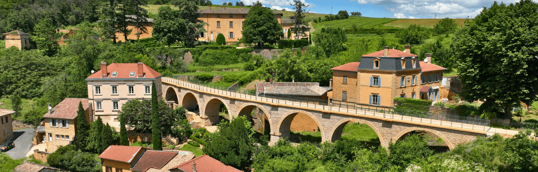 Pont de pierre menant au village de Jarnioux avec le château en toile de fond