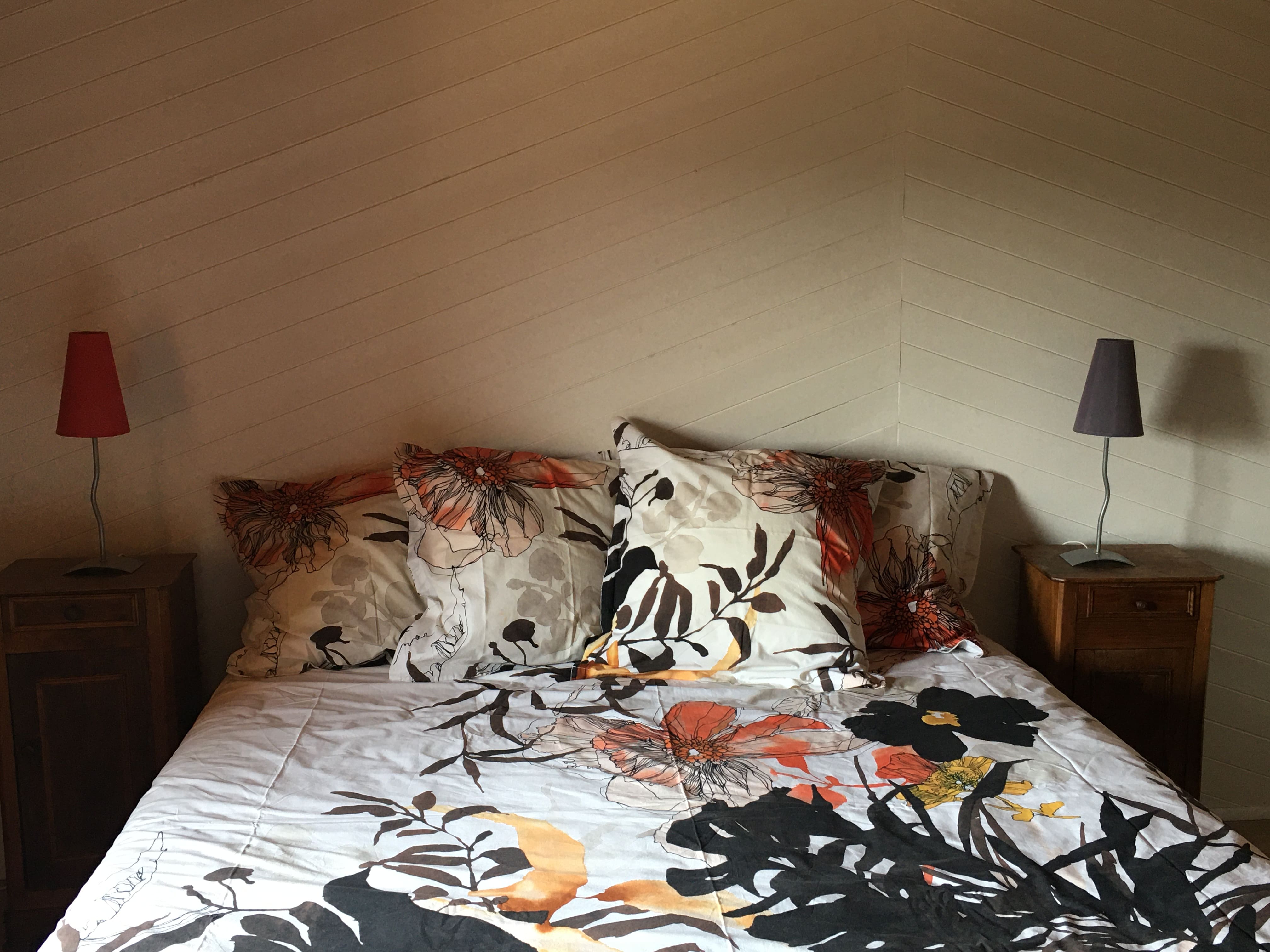 Chambre parentale chaleureuse du gîte avec linge en lin et tête de lit en bois naturel